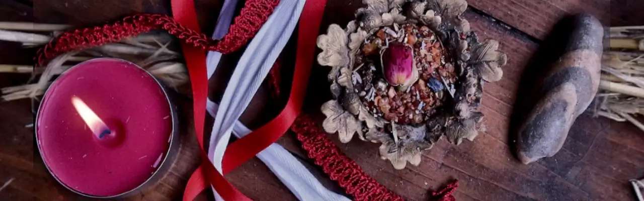 beltane altaar met rode kaars en rood-witte linten